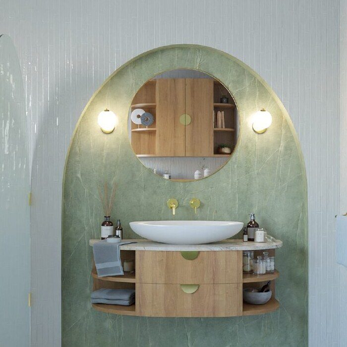 Close-up of an arched green stone bathroom vanity niche with a round mirror and wood cabinet