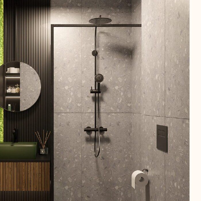 Close-up of a black shower fixture against grey stone tiles in the dark bathroom study